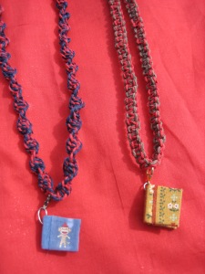 Necklaces with tiny book pendants. My sister made the tiny books. Both of them open up completely and have tiny pages which can be written upon. The blue book has a tiny sock monkey on it. 
